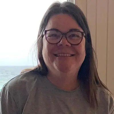 A woman with glasses smiling for the camera.